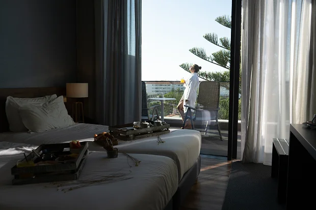 Resort manzaralı özel balkona sahip ikiz yataklı şık otel odası.