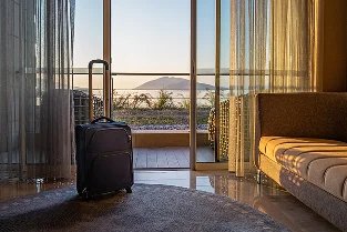 Manzaralı şık bir otel odasında yerleştirilmiş seyahat valizi.