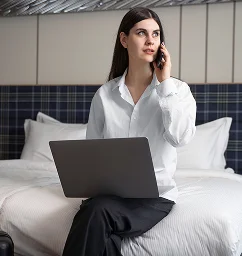 Telefonla konuşurken uzaktan çalışan kadın otel misafiri.